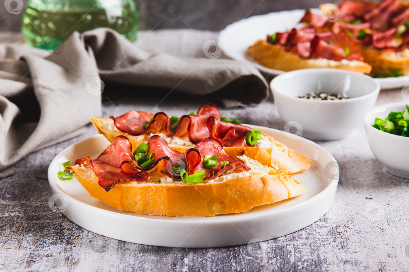 Скачать Запеченные бутерброды со сливочным сыром, прошутто и зеленью на тарелке на столе фотосток Ozero