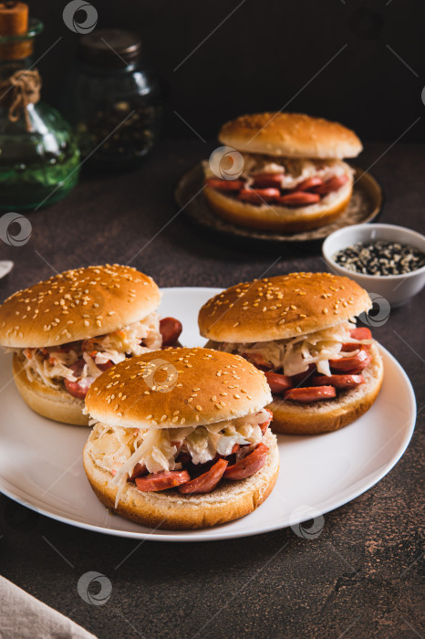 Скачать Бургеры с колбасой-гриль и капустным салатом на тарелке, вид сверху фотосток Ozero