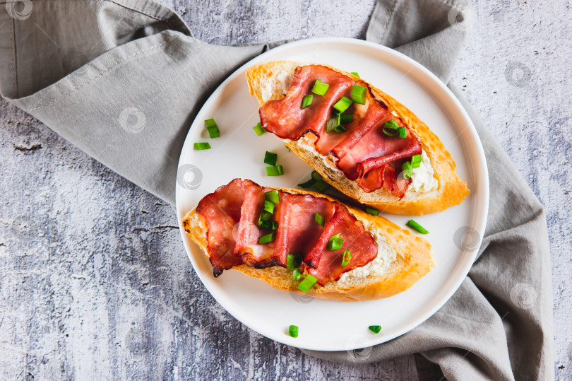 Скачать Запеченные бутерброды со сливочным сыром, прошутто и зеленью крупным планом на тарелке, вид сверху фотосток Ozero