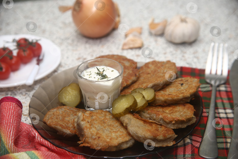 Скачать Блюдо жареные драники с овощами и приборами на столе фотосток Ozero