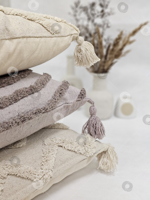 Скачать Сложенные в стопку подушки с кисточками в естественных тонах: натюрморт в стиле бохо-шик фотосток Ozero