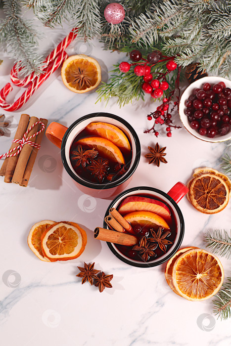 Скачать Глинтвейн со специями, звездчатым анисом, клюквой, апельсином, яблоком и корицей, согревающий зимний напиток в холодное время года, крепкий алкогольный или безалкогольный коктейль в железных кружках, праздничный рождественский грог фотосток Ozero
