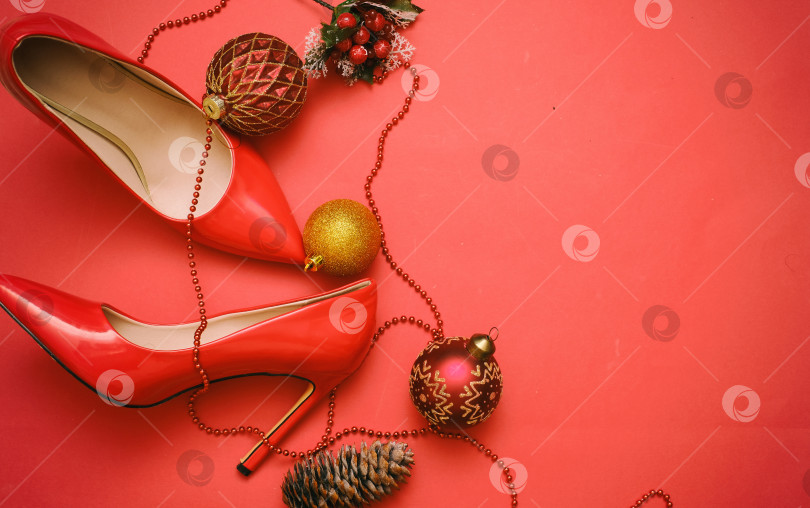 Скачать Женские туфли на шпильках рядом с рождественскими украшениями на красном фоне фотосток Ozero
