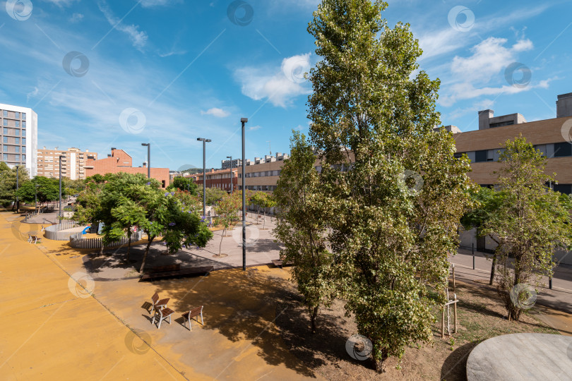 Скачать Солнечный внутренний двор и городское пространство между новостройками в фешенебельном районе Испании летним днем. Удобная концепция ландшафтного дизайна. Копировальное пространство фотосток Ozero
