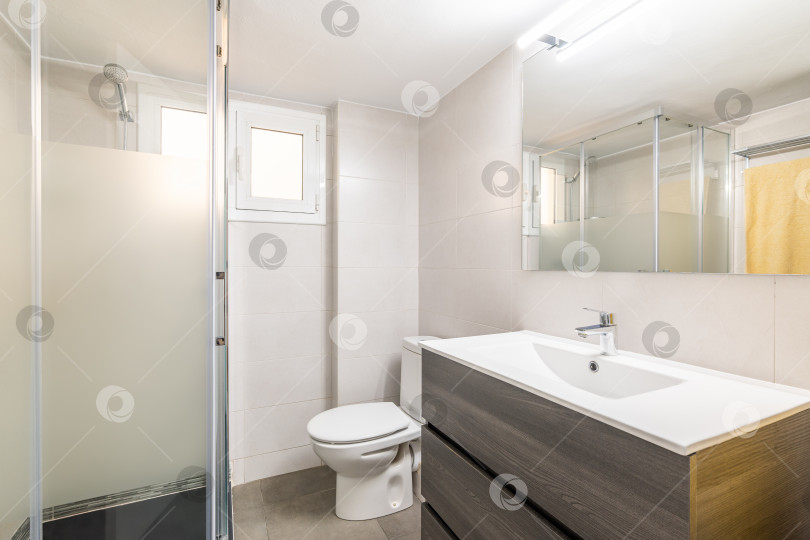 Скачать Удобный белый туалет с большой раковиной, зеркалом, унитазом и застекленной душевой кабиной в новом комфортабельном отеле. Концепция простого, но стильного дизайна ванной комнаты фотосток Ozero