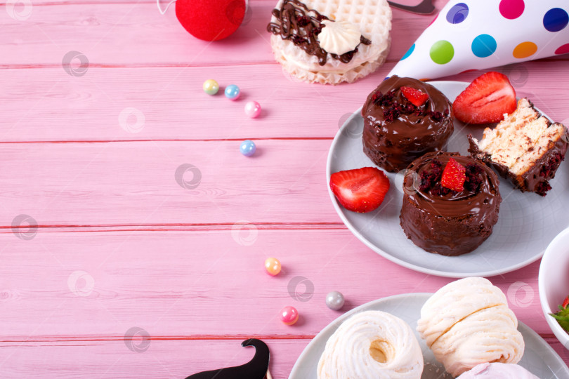 Скачать Шоколадные торты с клубникой и другие десерты для празднования дня рождения или детского праздника на розовом столе. фотосток Ozero