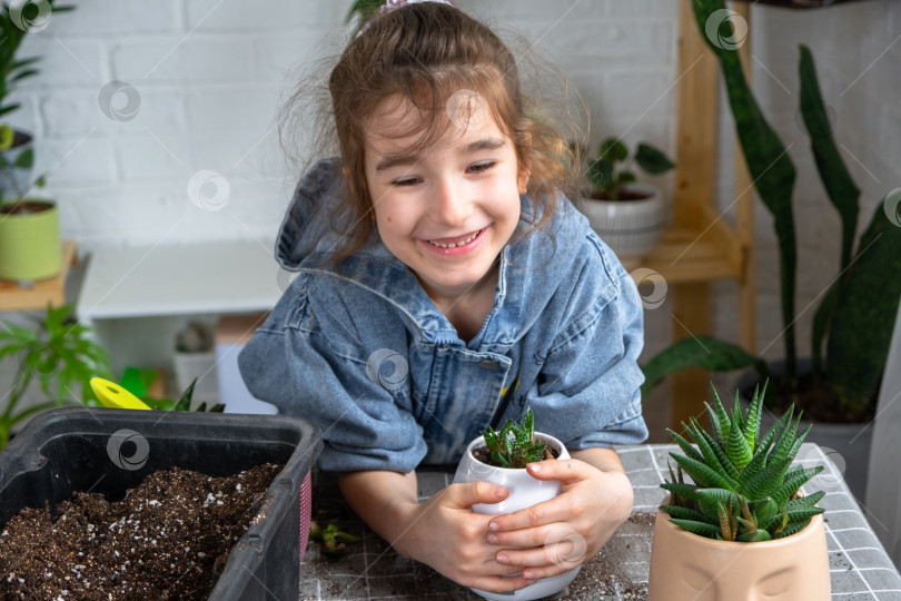 Скачать Счастливая девушка обнимает свое любимое растение алоэ в горшке, пересаживая его фотосток Ozero