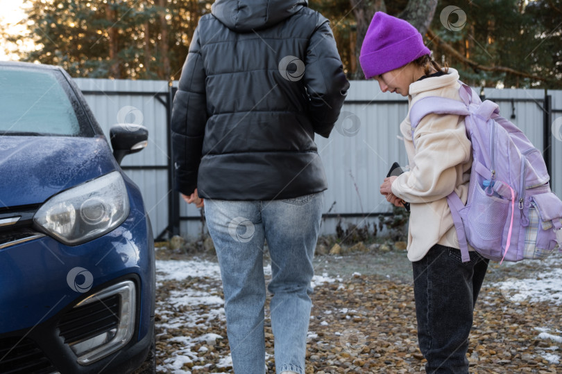 Скачать Мама сопровождает и сажает в машину девочку-школьницу с рюкзаком, чтобы отвезти ее в школу фотосток Ozero