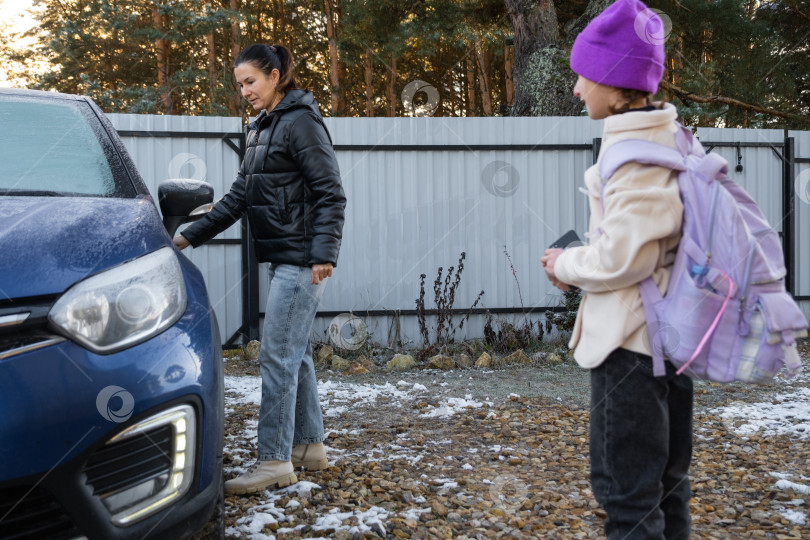 Скачать Мама сопровождает и сажает в машину девочку-школьницу с рюкзаком, чтобы отвезти ее в школу фотосток Ozero