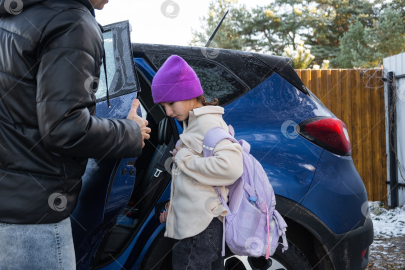Скачать Мама сопровождает и сажает в машину девочку-школьницу с рюкзаком, чтобы отвезти ее в школу фотосток Ozero