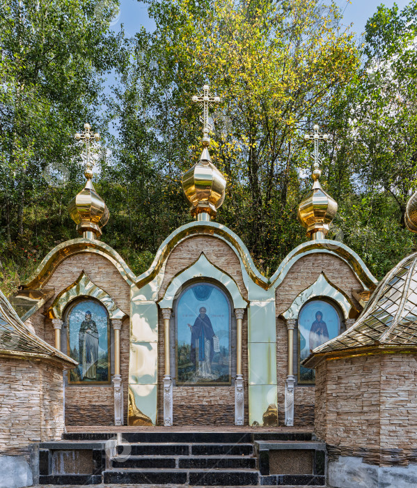 Скачать Крупный план павильона Святого источника в Радонеже с тремя золочёными куполами, иконами святых и отделкой из камня и полированной латуни. фотосток Ozero