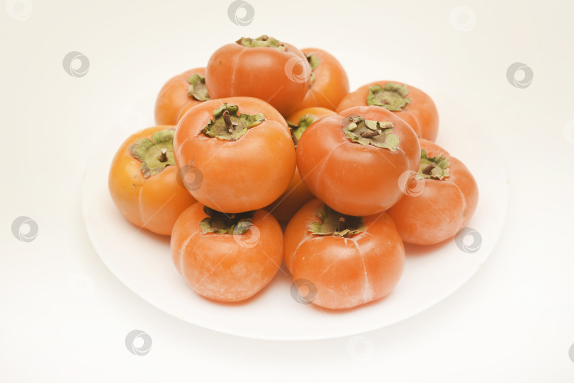 Скачать Оранжевые плоды хурмы. Спелая хурма на тарелке. фотосток Ozero