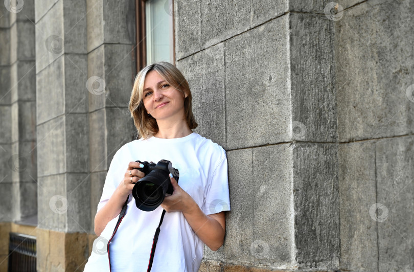 Скачать женщина-фотограф с фотоаппаратом в руках прогуливается по улицам города фотосток Ozero