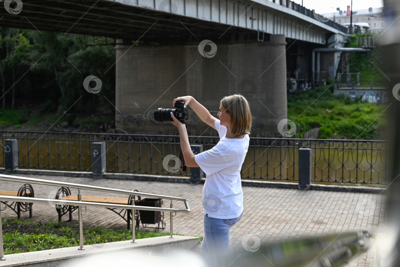 Скачать женщина-фотограф с фотоаппаратом в руках прогуливается по улицам города фотосток Ozero