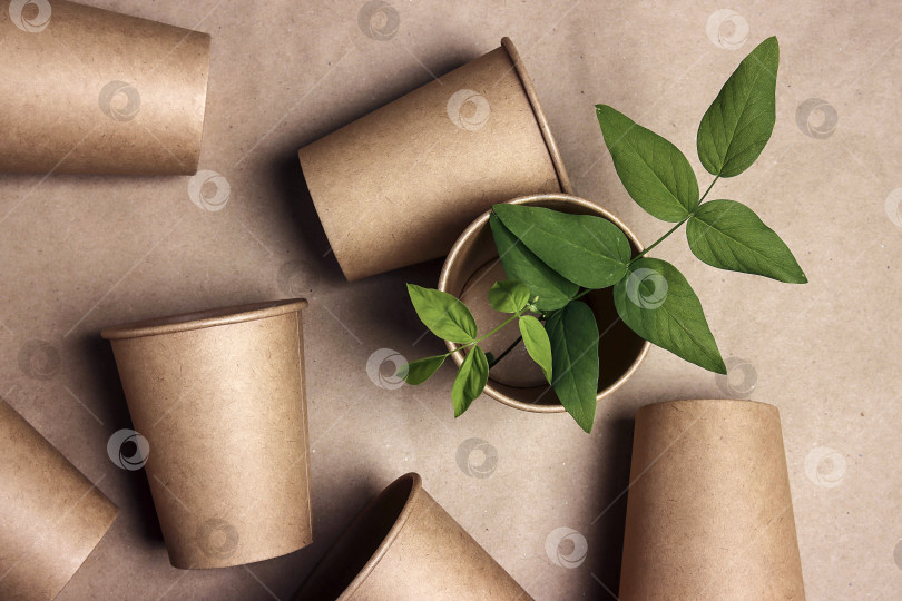 Скачать Набор экологически чистых чашек для приготовления кофе с зелеными листьями на фоне коричневой бумаги. фотосток Ozero