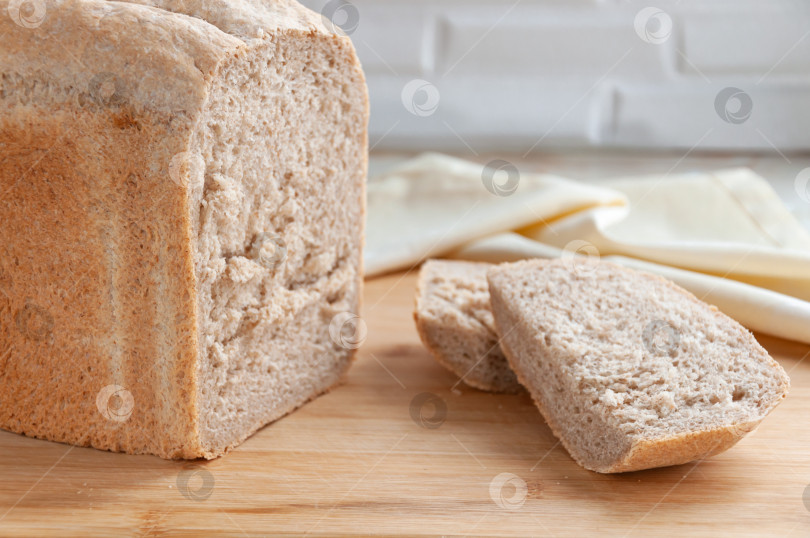 Скачать Домашний свежий хлеб. Свежеиспеченный хлеб выложите на деревянную доску в виде надреза. Ломтики хлеба. фотосток Ozero