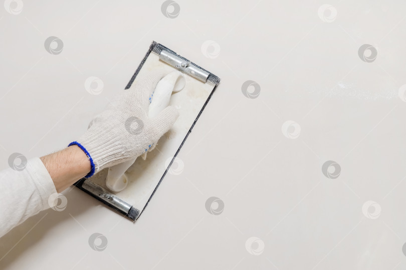 Скачать Рука рабочего и инструмент для шлифования шпаклевки. фотосток Ozero
