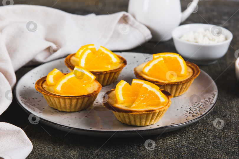 Скачать Мини-тарталетки с творогом и апельсином на тарелке на столе фотосток Ozero