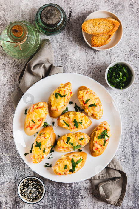 Скачать Запеченные бутерброды с крабовым салатом и зеленью на тарелке на столешнице в вертикальном положении фотосток Ozero