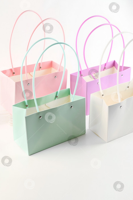 Скачать Подарочные пакеты с цветами пастельных тонов с ручками на белом фоне. Декоративная упаковка для букетов, используемая в цветочных магазинах и цветочных витринах. фотосток Ozero
