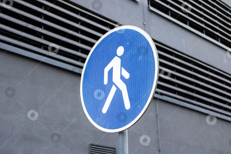 Скачать Минималистский городской пейзаж с ярким синим пешеходным знаком, подчеркивающим безопасность проезда фотосток Ozero