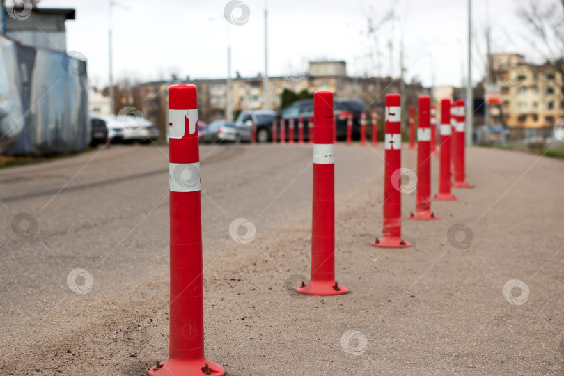 Скачать Красные столбы-ориентиры, красочные указатели безопасности, установленные вдоль дорожки, ведущей к отдаленному городскому пейзажу фотосток Ozero