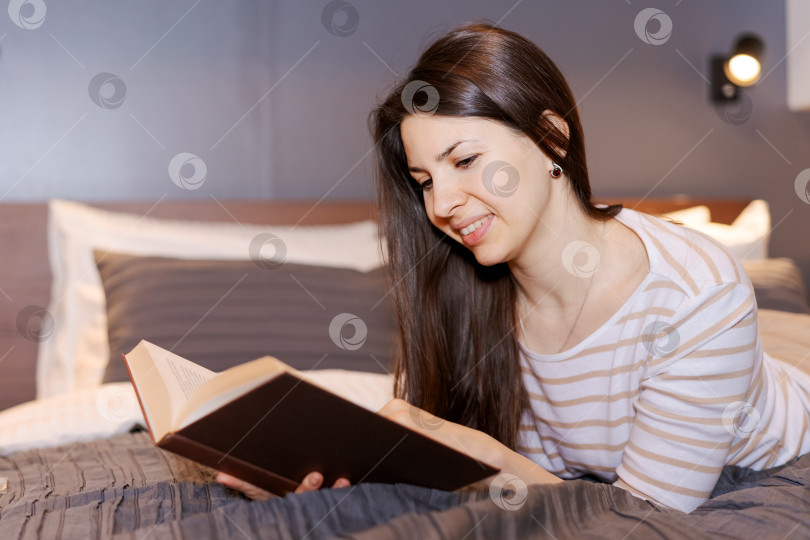 Скачать Женщина читает книгу на своей кровати фотосток Ozero