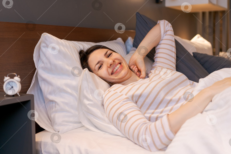Скачать Женщина улыбается и лежит в постели на белой подушке фотосток Ozero