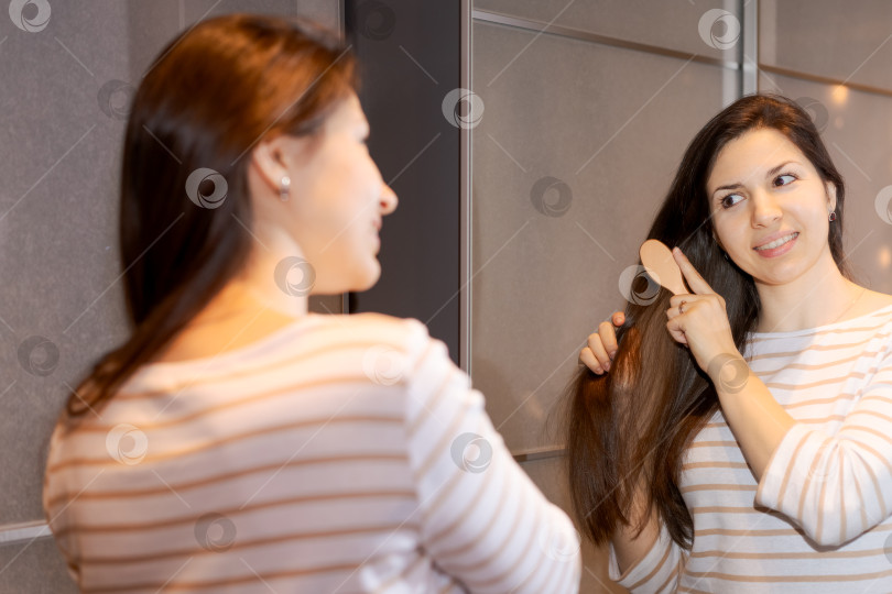 Скачать Женщина расчесывает волосы перед зеркалом фотосток Ozero