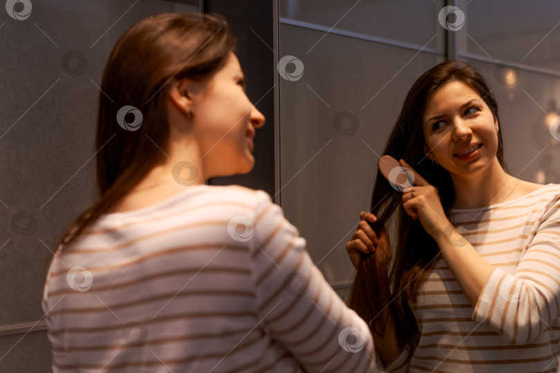 Скачать Женщина расчесывает волосы перед зеркалом фотосток Ozero
