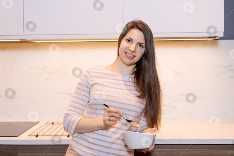 Скачать Женщина улыбается и ест кашу из миски фотосток Ozero