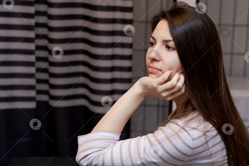 Скачать Женщина с длинными каштановыми волосами сидит за столом, закрыв лицо руками фотосток Ozero