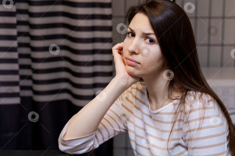 Скачать Женщина сидит, подперев голову рукой, и смотрит вниз фотосток Ozero