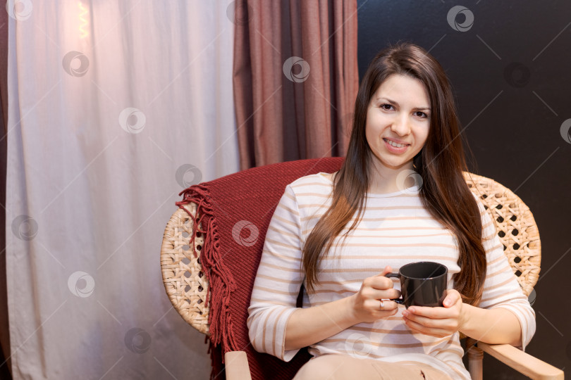 Скачать В кресле сидит женщина с чашкой в руке фотосток Ozero
