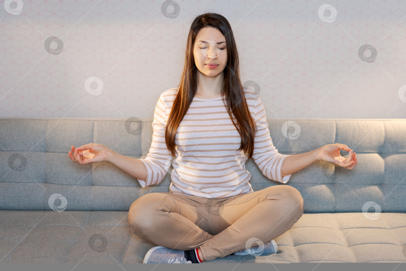 Скачать Женщина сидит на диване и медитирует фотосток Ozero