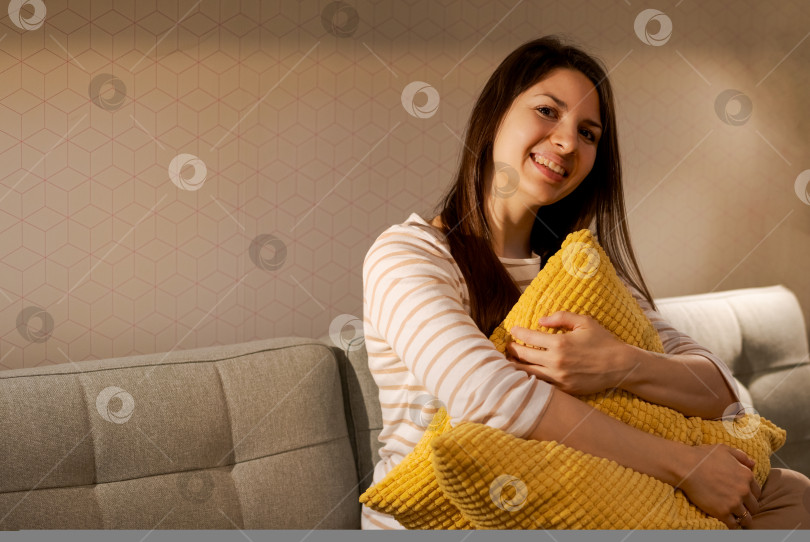 Скачать На диване с желтой подушкой сидит женщина фотосток Ozero