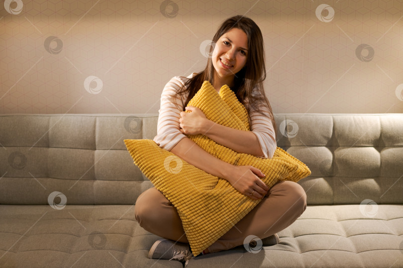 Скачать На диване с желтой подушкой сидит женщина фотосток Ozero