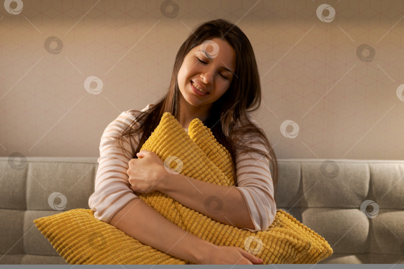 Скачать На диване сидит женщина с желтой подушкой на коленях фотосток Ozero