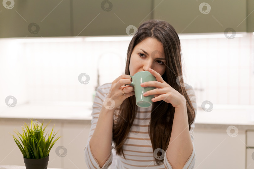 Скачать Женщина пьет кофе из зеленой кружки фотосток Ozero