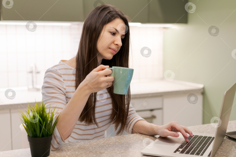 Скачать Женщина сидит за столом с ноутбуком и чашкой кофе фотосток Ozero
