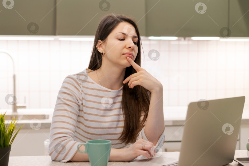 Скачать Женщина сидит за столом с ноутбуком и чашкой кофе фотосток Ozero
