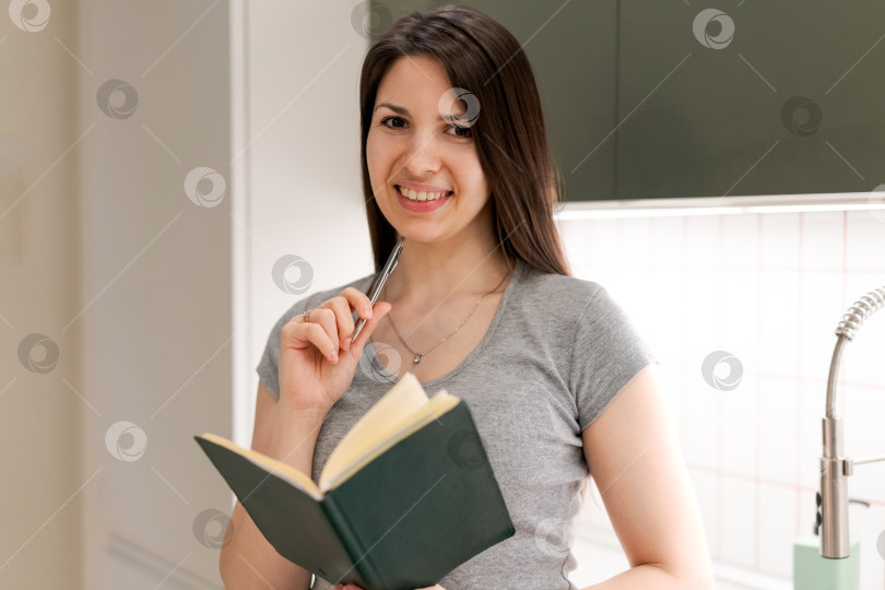 Скачать Женщина улыбается и держит в руках ручку и книгу фотосток Ozero