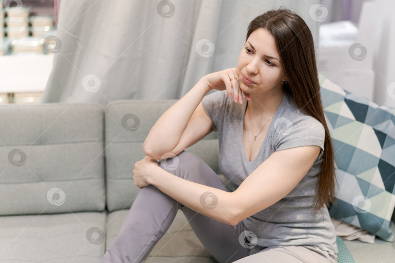 Скачать Женщина сидит на диване, положив руки на колени фотосток Ozero