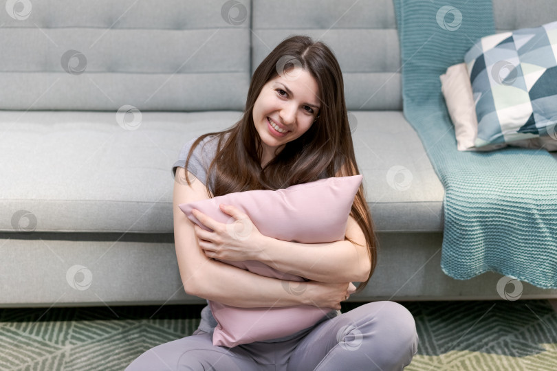 Скачать На полу сидит женщина с розовой подушкой в руках фотосток Ozero