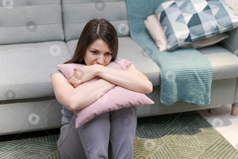 Скачать На полу сидит женщина с подушкой на коленях фотосток Ozero