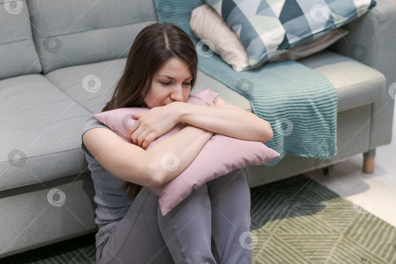 Скачать На полу сидит женщина с подушкой на коленях фотосток Ozero