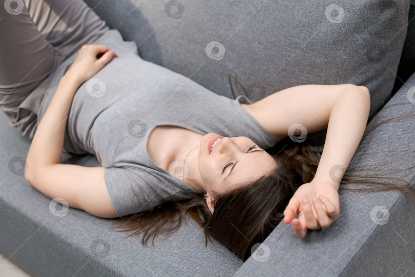 Скачать Женщина лежит на диване, раскинув руки и ноги фотосток Ozero