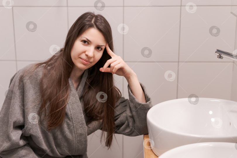 Скачать Женщина сидит перед раковиной, подперев голову рукой фотосток Ozero