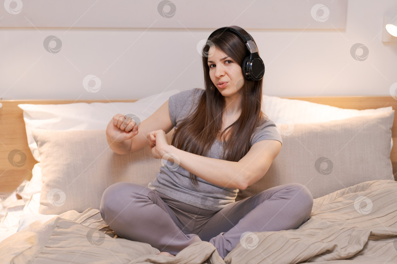 Скачать На кровати сидит женщина с наушниками на голове фотосток Ozero