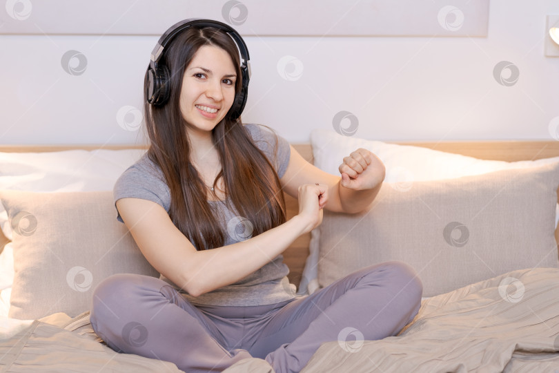 Скачать На кровати сидит женщина с наушниками на голове фотосток Ozero